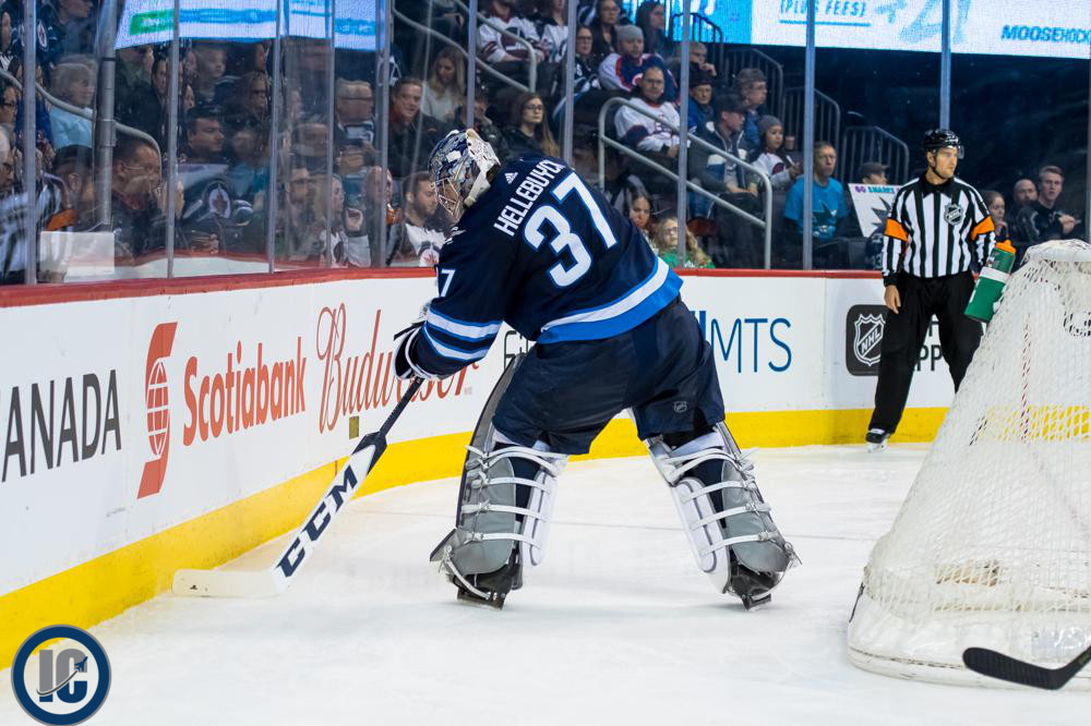 Connor Hellebuyck plays the puck