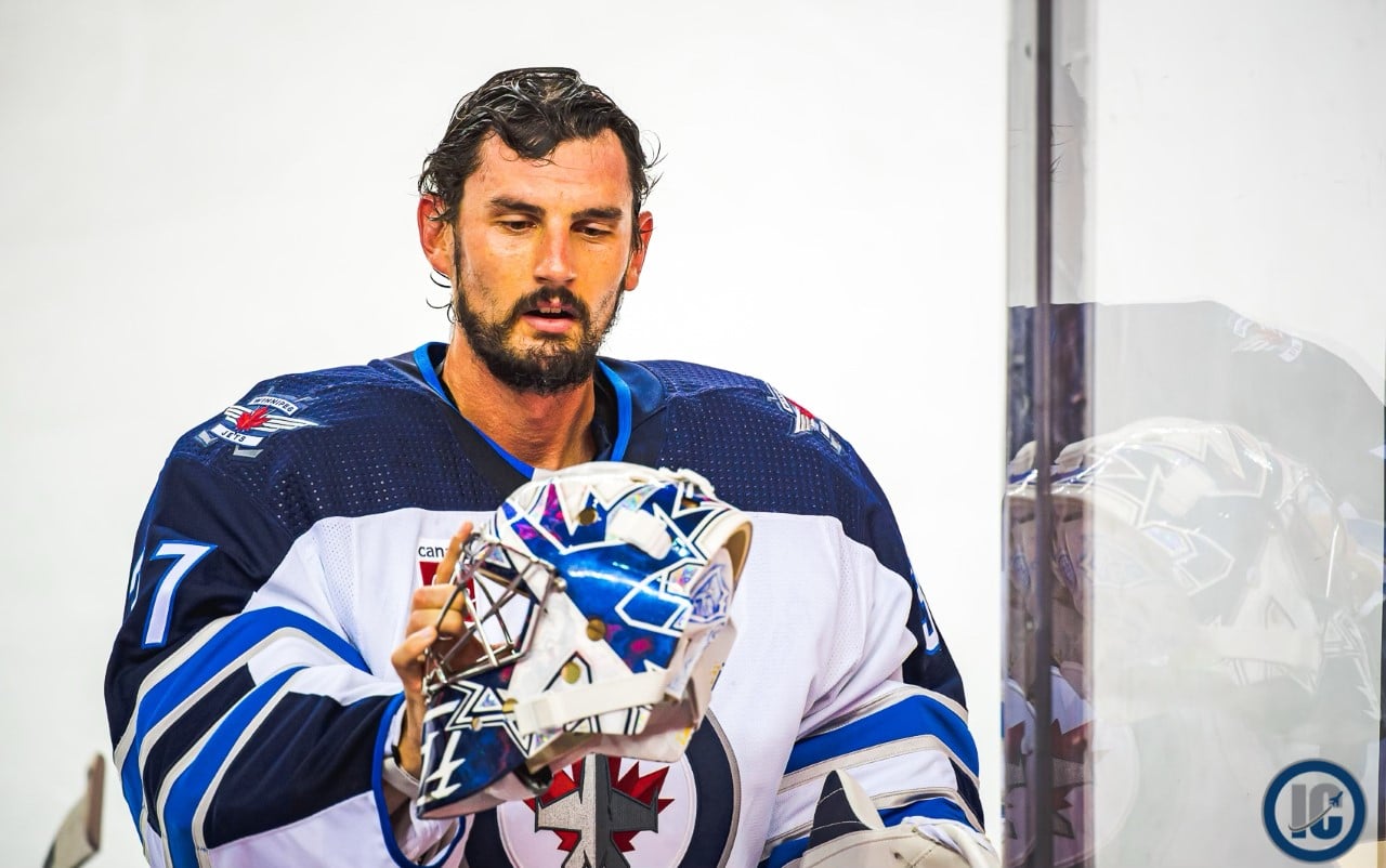 Connor Hellebuyck looking at mask